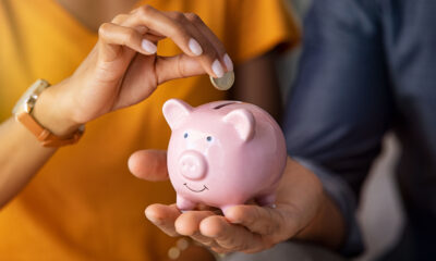 Hands placing a coin into a pink piggy bank